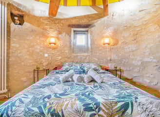 Chambre d’hôte dans un moulin rénové – lit double, serviettes pliées, murs en pierre et lumière natu