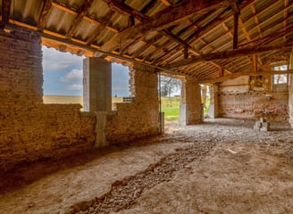 Ancienne grange en rénovation, sol décaissement et charpente visible, photo de suivi de chantier