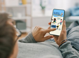 Man lies on a sofa, reads book on cell phone