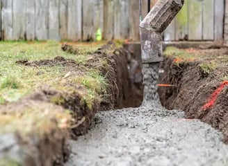 a concrete slab being poured into a trench