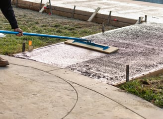 a person using a broom to clean a sidewalk