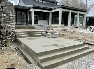 a house with a large concrete patio with steps leading up to a large house