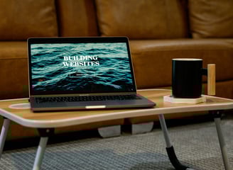Laptop displaying the words ‘Building Websites’ on the screen, placed on a desk.