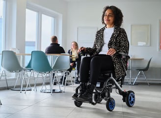 A folding powered wheelchair being used in a cafe by a happy lady enjoying a day out with her Carbon