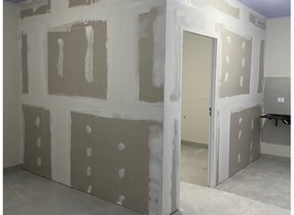 a room with a wall of drywalled walls and a door