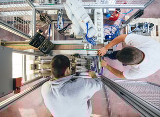 two men working on a robotic machine that is being worked on and upgraded