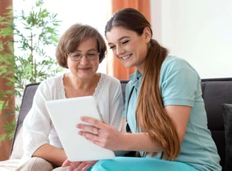nurse and patient smiling while nurse is helping patient