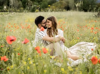 Couple sitting in a poppy field — heads together, smiling and intertwined in Provence