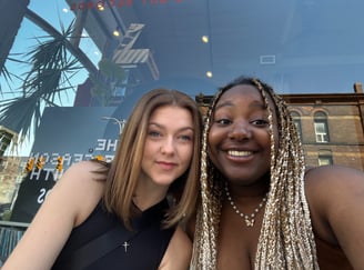 Two girls sitting in front of a store window