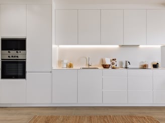 Open-plan kitchen with white cabinets and state-of -the-art appliances for contemporary apartment