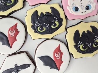 Cookies with yellow or pink icing, designed with How to Train Your Dragon characters