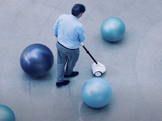 Image of a middle aged man navigating large, round bollards with the Glide device.