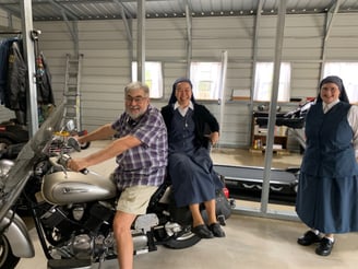 Motorcyclist giving rides to Catholic nuns.
