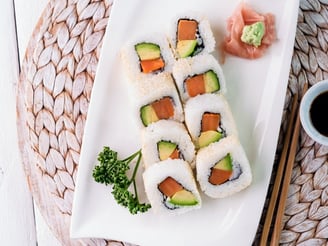 a plate of sushi rolls with chopsticks and sauce