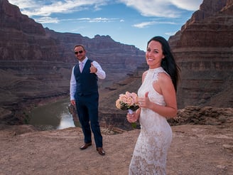 a man and woman standing on a cliff overlooking a canyon