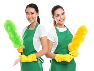 two women in green aprons holding cleaning supplies