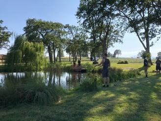 a man standing in a field with a boat in the water