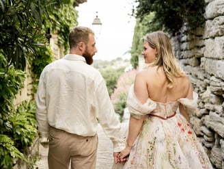 Couple walking hand in hand, looking at each other — woman in floral dress, Provence couple session