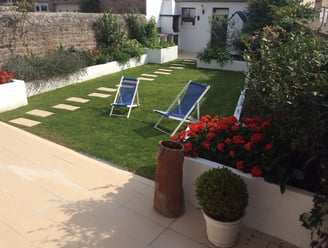 Jardin aménagé avec bordures maçonnées, pelouse soignée et dalles décoratives