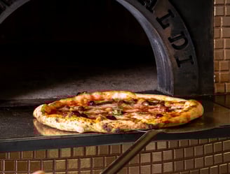 Pizza artigianale con olive appena sfornata dal forno a legna di AndrèsRosa Pizzeria ad Alseno