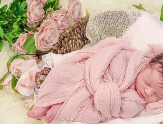 a newborn baby in a basket with flowers