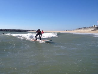 A young surfer riding a small unbroken wave in a surfing class