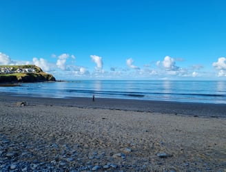 Early morning beach and Borth headland with small waves and smooth clam  blue sea and sky