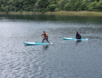 A paddle board coach demonstrating a step back turn to a student