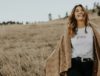 Femme souriant dans un champ en pleine nature qui porte un tee-shirt FORMASPARK