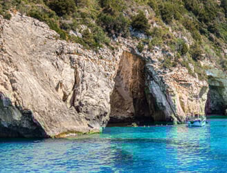a boat in the water near a cliff