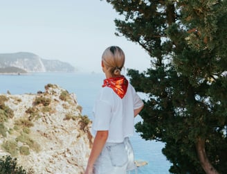 a woman standing on a hill overlooking the ocean