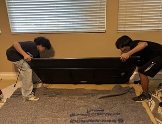 TwoTwo people carefully carrying a TV during a move.