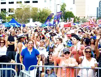 a crowd of people standing in front of a fence