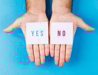 two hands holding up a card with the words yes no