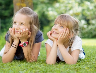 portait d'enfants souriants allongés dans l'herbe