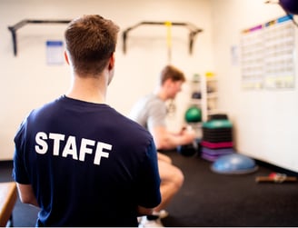 coach with staff shirt training a man in a gym