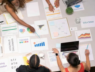 A group of people discussing marketing strategies with various documents and charts spread out on a table
