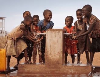 Children drinking clean water from a well in Africa