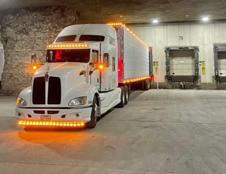 a semi truck with a trailer backed into a dock at an amazon facility