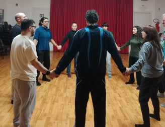 a group of people holding hands in a circle, classe di esercizi di bioenergetica