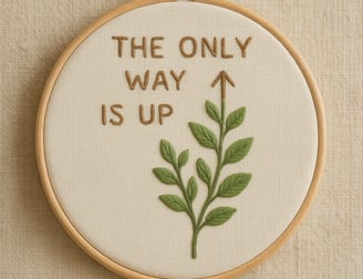 Embroidery hoop on a neutral background featuring the motivational phrase ‘The Only Way Is Up’