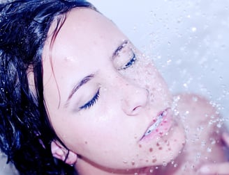 a woman in the shower letting the water hit her face