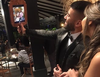 Um homem e uma mulher tirando uma selfie com espelho de mão em uma festa.