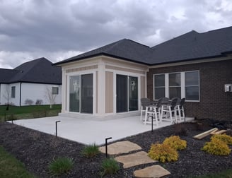 New patio enclosure with two large sliding-glass doors leading out onto a concrete slab patio.