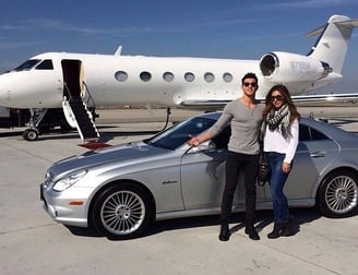 a man and woman standing in front of a private jet plane