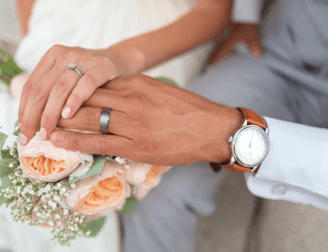 a just married couple holding their hands on a bouquet