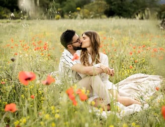 Editorial engagement photo of a couple kissing in a Provence poppy field by a fine art photographer