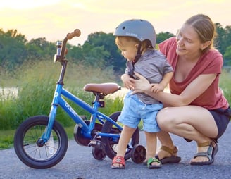 a Mom and her son with his bicycle in a park