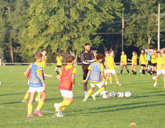 a group of young people playing soccer on a field