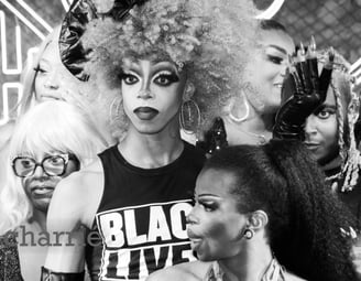 drag queen wearing shirt that says black lives matter looking out surrounded by performers